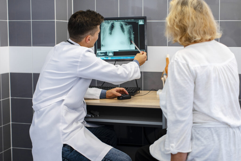 a doctor examines a chest x-ray for signs of pneumonia while a patient looks on