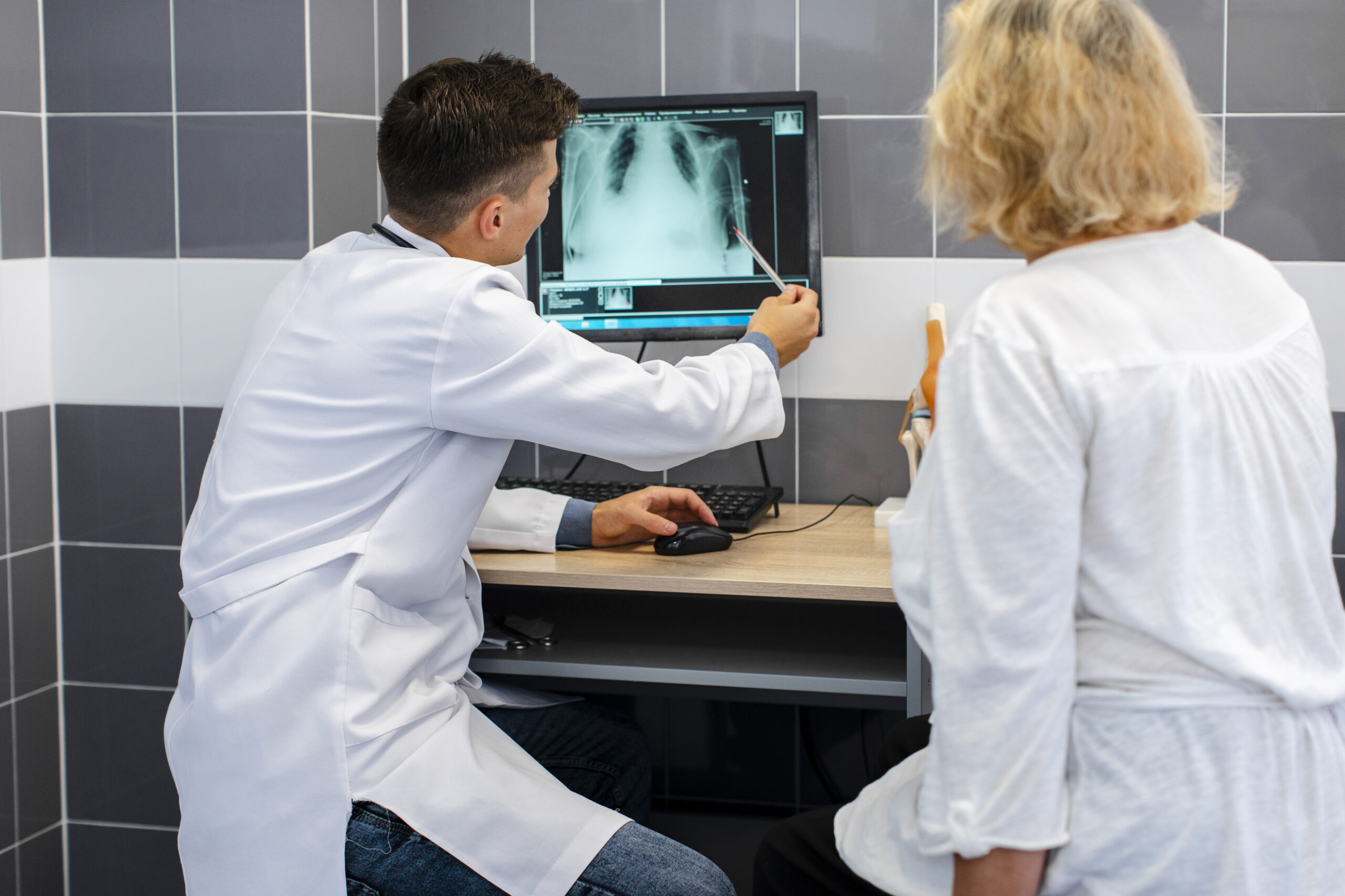 a doctor examines a chest x-ray for signs of pneumonia while a patient looks on