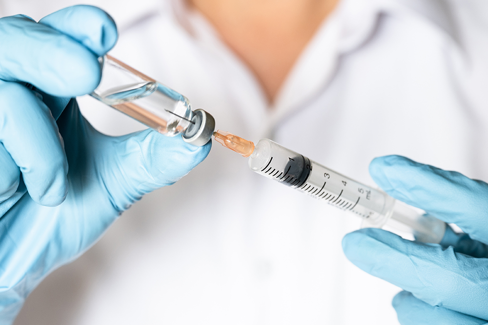 a practitioner fills a syringe with a vaccine