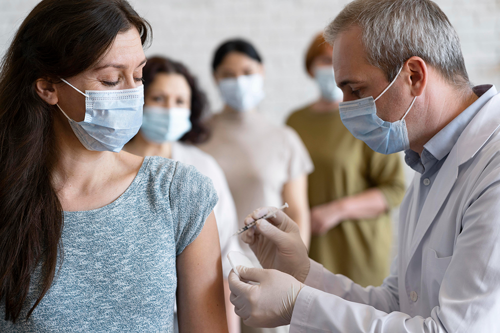line of masked people in a doctor's office receiving vaccinations
